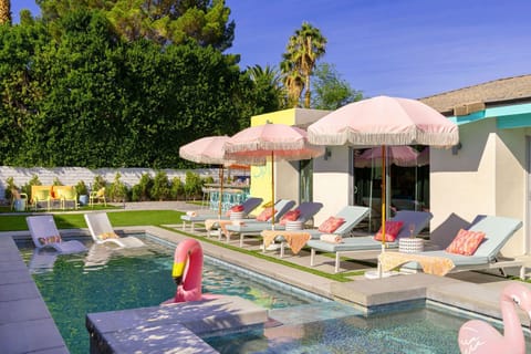 Resort-style pool with shallow ledge, loungers, and pink umbrellas