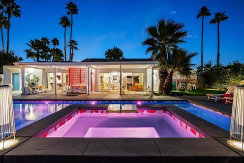 Spa and pool glowing at night with mountain backdrop and palm trees