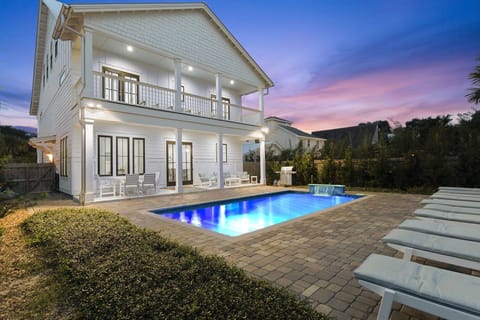Evening exterior w/ glowing pool lights & a relaxed nighttime vibe.