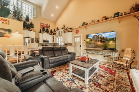 Open concept main level living room, kitchen, and dining with 83 inch TV.