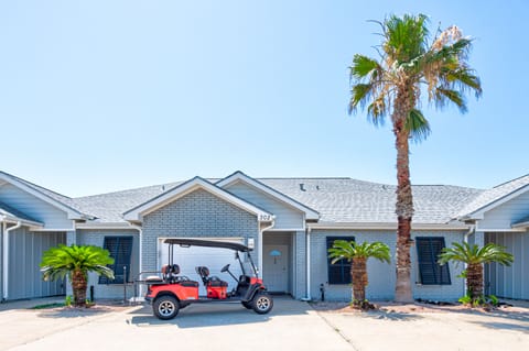 Charming coastal property with palm trees and golf cart parking in a sunny, tropical setting.