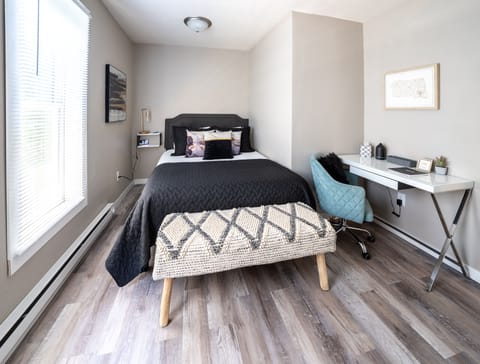 First queen bedroom, with TV, desk, charging pots, lamp, extra blanket, and fan