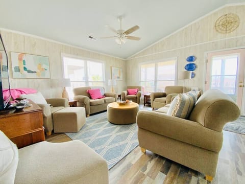 Comfortable living room with ceiling fans, large windows, and sky-blue ceiling. 