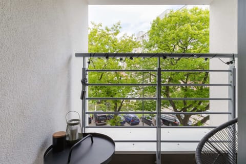 A compact balcony with a simple table and chair set, surrounded by greenery, making it a perfect spot for outdoor relaxation.