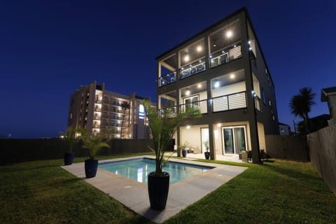 Luxury modern home glowing beside private pool