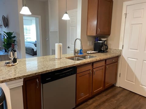 Kitchen features stainless steel appliances and granite countertops + lots of cabinet space full of kitchenware.