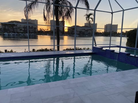 Pool and spa with marble tiled decking enclosed in screened lanai