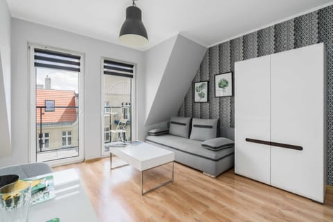 Living area with a gray sofa and a large window bringing in natural light.
