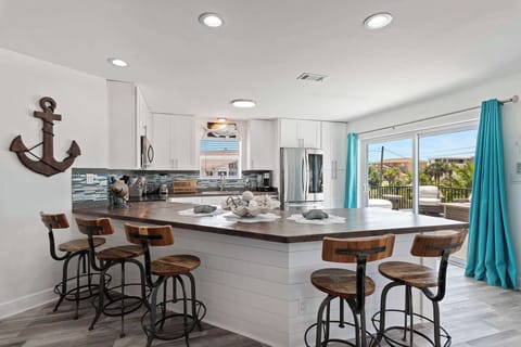 Open kitchen w/ a wide island, bar seating, & views into the living space