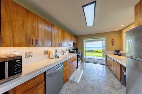 Bright galley kitchen with warm wood cabinets modern appliances and ocean views