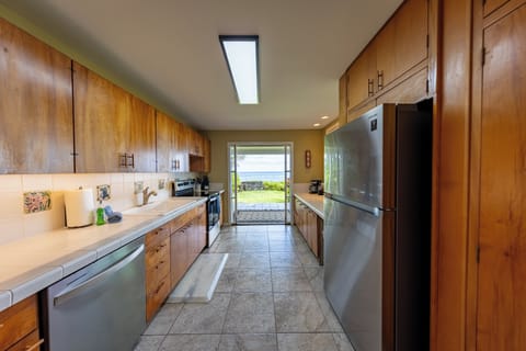 Bright galley kitchen with warm wood cabinets modern appliances and ocean views