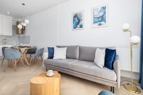 Living room with a gray sofa, wooden coffee table, and bright natural lighting from large windows.
