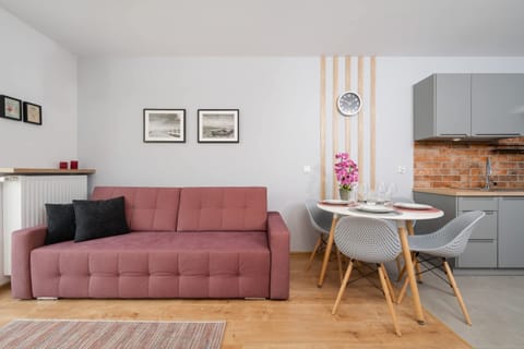Bright and cozy living area with a pink sofa, dining table, and wall art accents.
