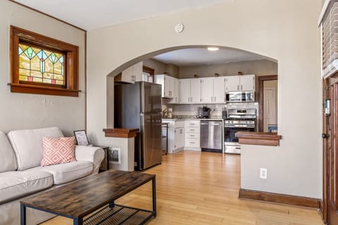 Living room with a sofa and coffee table connected to the kitchen through a wide arched opening.