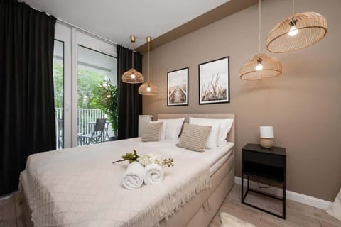 Bedroom with a large bed, beige bedding, elegant lighting, and decorative wall art.
