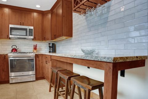Seating for 3 at the kitchen breakfast bar with bar rack, tiled backsplash and granite countertops