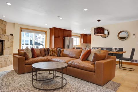 Brown leather sectional couch in the living room with circular modern wooden coffee table