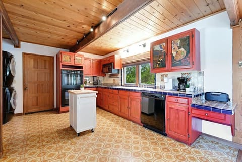 Spacious retro‑inspired kitchen with double ovens, rolling island, tile counters, and in‑home laundry—well‑equipped for longer stays and family gatherings.