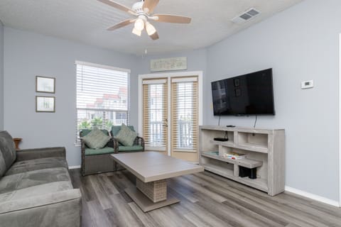 Unwind in your spacious living room with plush seating, modern entertainment center, and natural light streaming through elegant shutters.