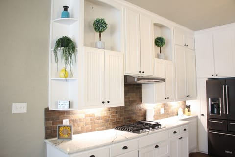 Luxurious Kitchen with white cabinets, quartz countertops and gas stove