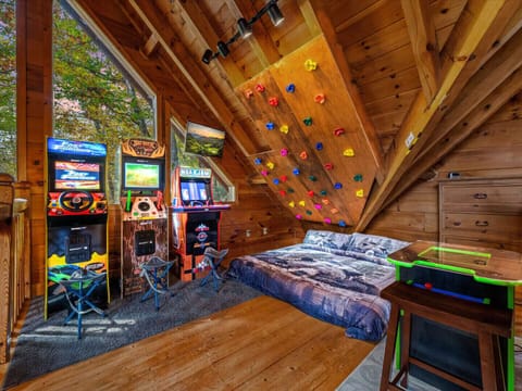 Kids’ game room with arcade machines, climbing wall, and king bed