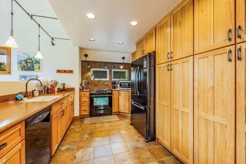 Spacious kitchen with ample natural wood cabinetry, modern appliances, and tile flooring.