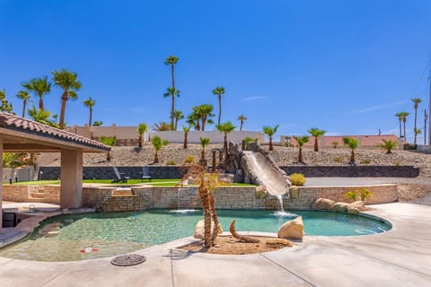 Resort-style backyard oasis featuring a sparkling pool, thrilling waterslide, and desert-inspired landscaping