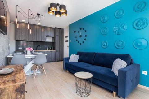 A cozy living room with a gray sofa and a blue accent wall decorated with circular patterns. There’s a small round coffee table and a pendant light above.