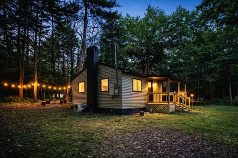 Tucked in the woods with a cozy deck and warm evening lighting — perfect!