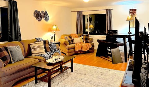 Living room with cozy accents including throw pillows, blankets, tables and lamps.