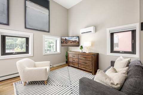 Bright studio space w/ cozy seating, patterned rug & large windows that fill the room w/ natural light.