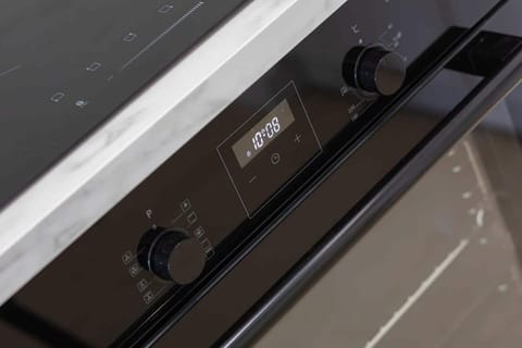 A close-up of a black oven with modern controls and a glossy finish, blending functionality with stylish design.

