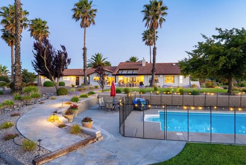 Stunning Mediterranean-style retreat with lush palm trees and a sparkling pool, set against a backdrop of mature landscaping and inviting outdoor spaces perfect for your desert getaway.