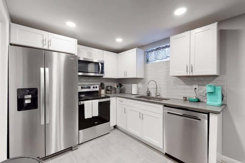 Bright kitchen with pots, pans, spices, and stainless appliances. 