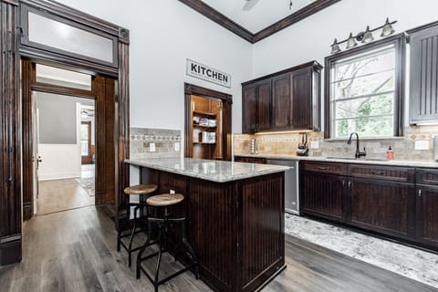 Kitchen with plenty of dishes, large fridge, an island, and pantry.
