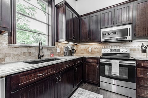 Kitchen with microwave, oven, stove top, and coffee maker.
