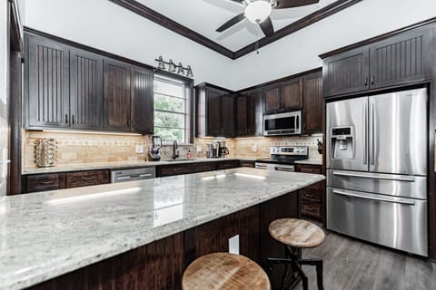 Kitchen with plenty of dishes, large fridge, and island, and pantry.
