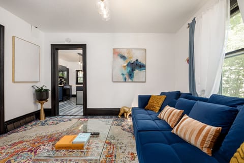 Open living space w/ plush blue sofas, colorful rug & easy flow to the dining area.