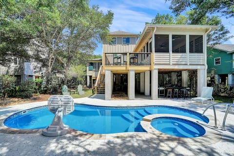 Modern elevated home featuring a private pool and hot tub with covered outdoor dining area beneath the main structure.