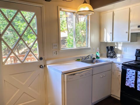 Kitchen with dinnerware, cookware, silverware, and appliances. 