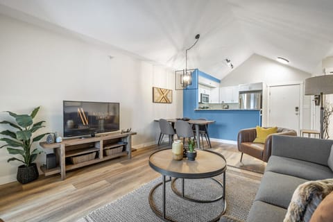 Living room with a large Smart TV, cozy seating options and access to the private balcony.