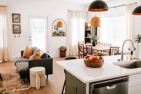 The kitchen opens up to the contemporary dining area, which features a large wooden table with seating for six.