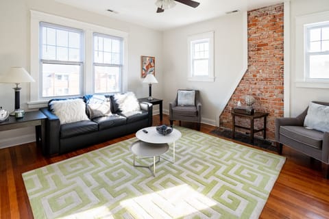 Relax in style with exposed brick accents, natural light, a cozy 3-seater sofa, two armchairs, a Roku TV, and games like Scrabble.