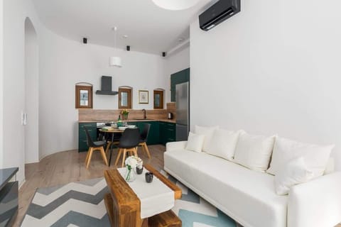 Another perspective of the living room, showcasing a sleek design with a white sofa, decorative rug, and TV unit.