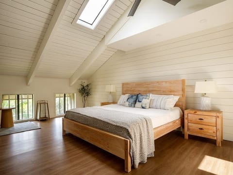 Drift off in luxury! This upstairs bedroom features a plush king-size bed and sunlit skylight for ultimate relaxation.