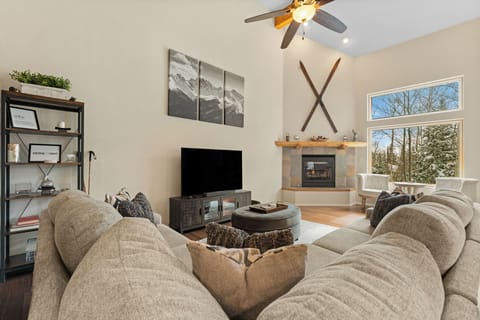 Sink into plush seating while your favorite show plays and the fireplace warms the room. Natural light pours through tall windows framing peaceful wooded views beyond.
