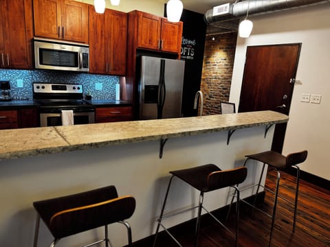 Kitchen with concrete countertops, stainless appliances and cozy eat-in bar. 