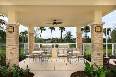 An inviting outdoor grill area offers a great space for barbecues, surrounded by palm trees and a fenced garden for privacy.