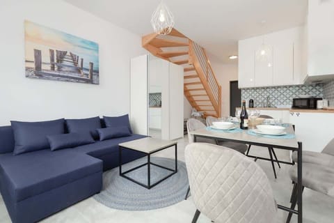 A stylish living room featuring a blue sofa, a coffee table, and a dining area with modern chairs, blending comfort and practicality.