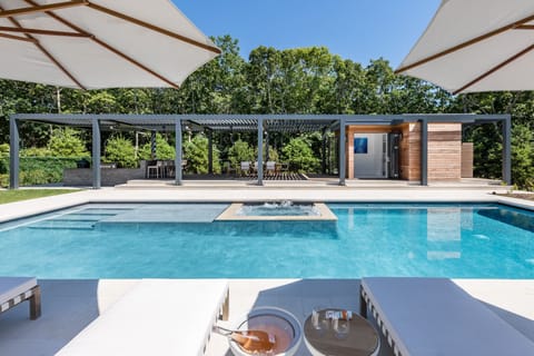 Pool area viewed from side with teak loungers and umbrellas